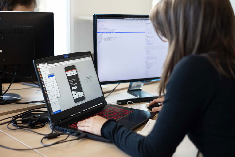 Image mise en avant – Anaïs, développeuse chez Fotetsa, en train de travailler sur une application mobile hybride depuis son laptop Image mise en avant - Anaïs, développeuse chez Fotetsa, en train de travailler sur une application mobile hybride depuis son laptop